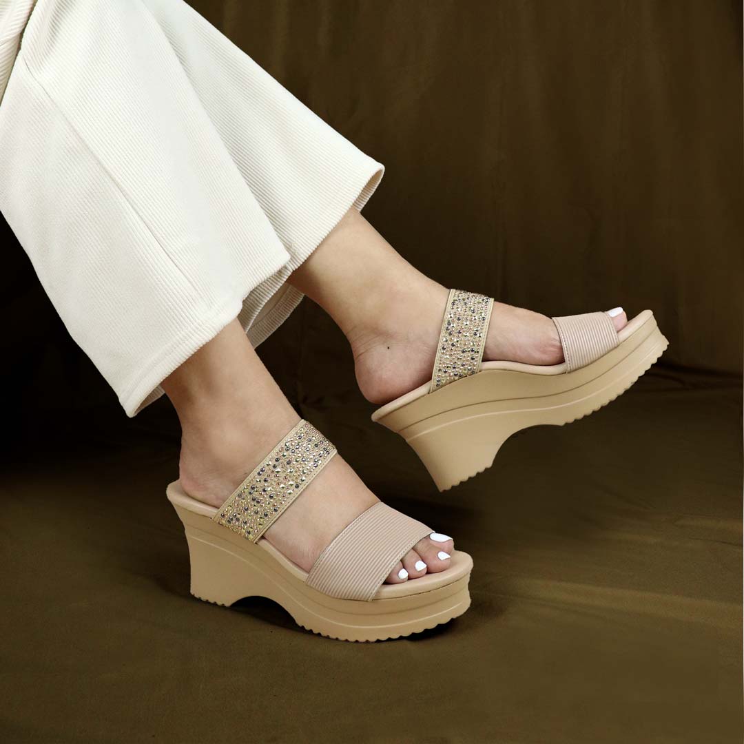 Model showcasing Thomas Chan's Strappy Rhinestone Cushioned Heels in cream. The heels feature a built-in cushioned footbed, a sleek front stripe, and a dazzling rhinestone strap at the back. Set against a bronze-colored backdrop, the image highlights the elegance and support of the design.