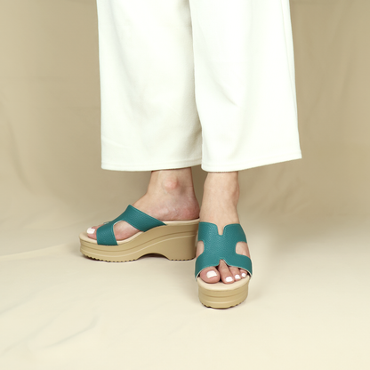 Model wearing Pebble Lychee H-strap Cushioned Heels in green and cream platform, featuring a 3-inch platform heel and integrated Thomas Chan® cushioned footbed, standing against a cream backdrop.