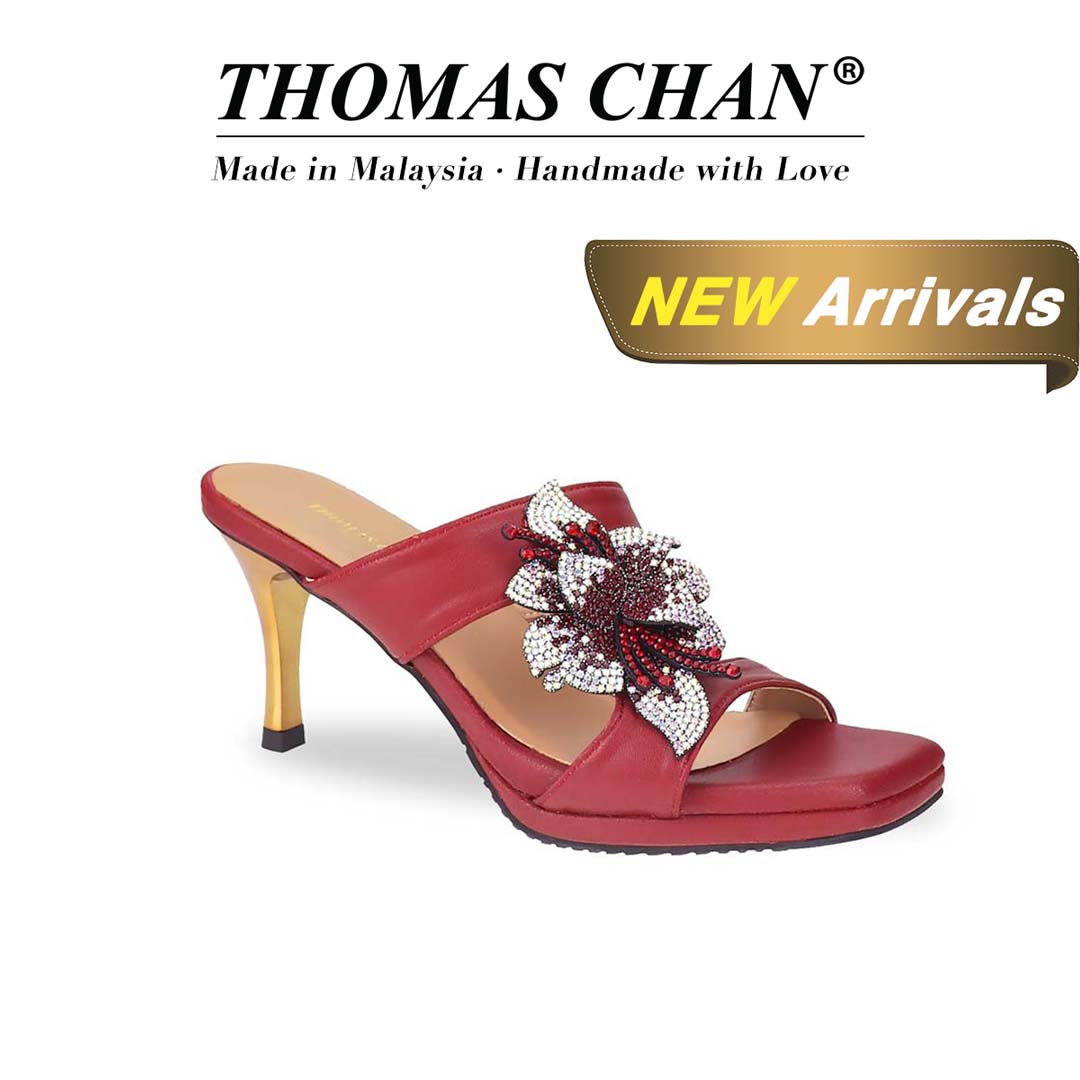 Diagonal view of Thomas Chan's Embellished Flower High Heeled Sandals in red, highlighting the intricately adorned floral decorations and a sophisticated 3-inch gold stiletto heel, "THOMAS CHAN®" brand displayed with "Made in Malaysia · Handmade with Love" below. Gold and white banner highlights special offer: "New Arrival"