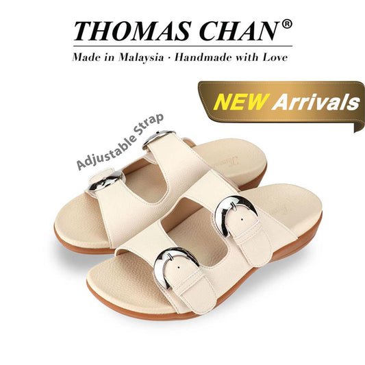 "Thomas Chan's Duo Buckle Slide-One flat sandals in ivory, featuring an elegant design with an arch-support footbed. The 'THOMAS CHAN®' brand is prominently displayed with 'Made in Malaysia · Handmade with Love' below. A gold and white banner highlights the special offer: 'New Arrival.' The sandals also feature an adjustable strap.