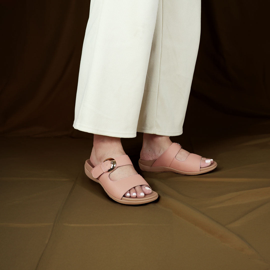 Model wearing size 37 Thomas Chan's Great Coverage Buckle flat sandals in rosy pink from the front view, standing. The sandals feature a comfort footbed with a 3cm flat platform. Behind the model is a bronze-coloured backdrop.