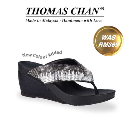 Image of a Suede Rhinestone Wedge Flip Flops from Thomas Chan in black colour. The sandal features a glossy design with a 3-inch wedge heel with arch-support footbed technology. A gold badge shows the original price was RM369, with text above reading "THOMAS CHAN® Made in Malaysia · Handmade with Love." & "New Colour Added"