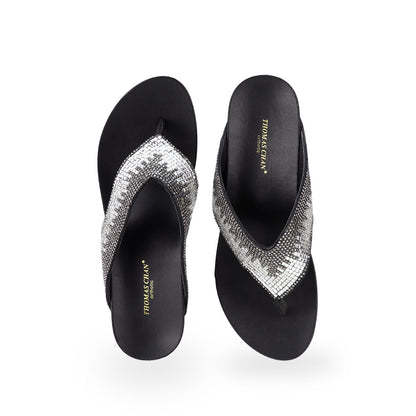 Front view of Thomas Chan Suede Rhinestone Wedge Flip Flops in black colour: Elevate your casual look with a touch of sparkle and comfort. These chic wedge flip flops, adorned with rhinestones, are perfect for adding a hint of glamour to your summer ensemble.