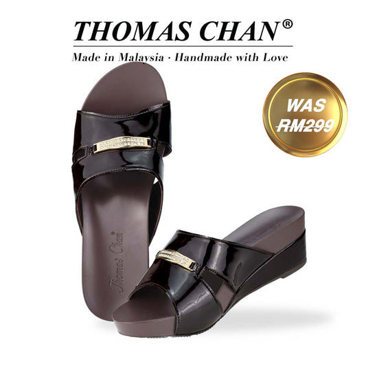 Thomas Chan's Mini Charm Low Wedge Sandals in dark chocolate, featuring small charm detail, a coverage design, and an arch-support footbed. "THOMAS CHAN®" brand displayed with "Made in Malaysia · Handmade with Love" below. Gold and white banner highlights special offer: "Was RM299."