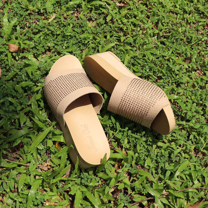 Thomas Chan Comfy Elegant Low Wedges in cream, featuring delicate rhinestone accents and a coverage design. The 2-inch wedge height and arch-support footbed offer both elegance and comfort. Set on a grassy outdoor surface, these wedges exude a chic, yet relaxed vibe.