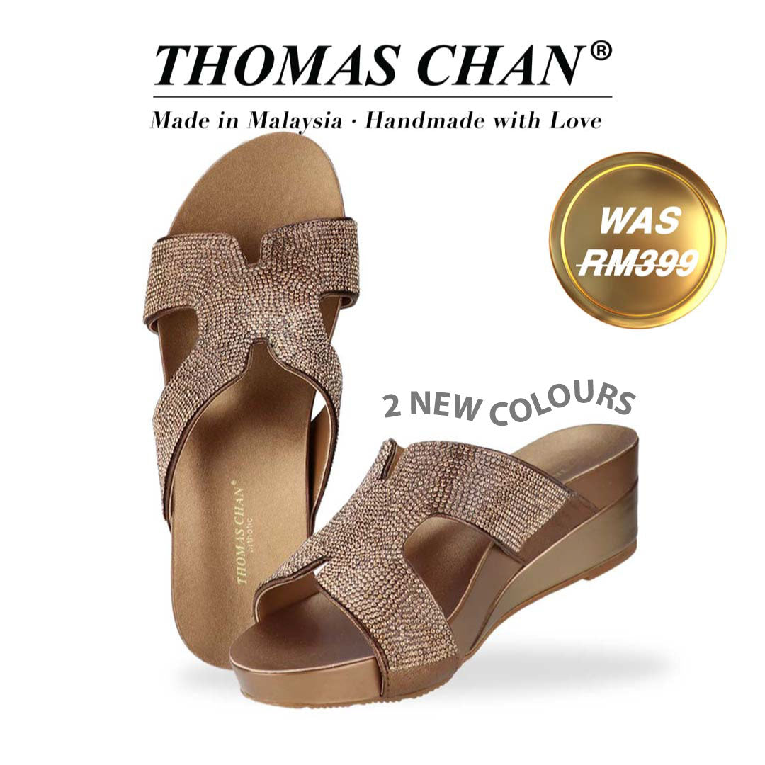 Thomas Chan's H-strap Glamour Stone Low Wedges in bronze, adorned with glamour rhinestone detailing ,and an arch-support footbed. "THOMAS CHAN®" brand displayed with "Made in Malaysia · Handmade with Love" below. Gold and white banner highlights special offer: "Was RM399." &"2 NEW COLOURS"