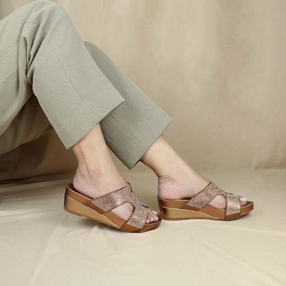  Model showcasing Thomas Chan's H-strap Glamour Stone Low Wedges in bronze, adorned with glamour rhinestone detailing ,and an arch-support footbed with 2-inch height wedges, set against a cream backdrop.