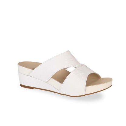 Diagonal view of Thomas Chan's Pebble Lychee Everyday Low Wedge Slides in pastel white, featuring an arch-support footbed. 