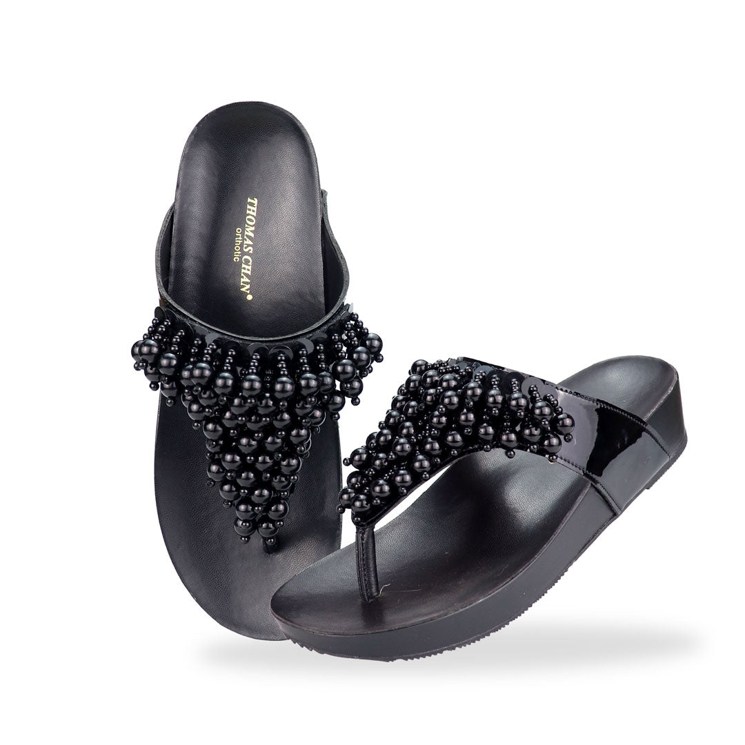 Full view of Thomas Chan's Pearl Tassel Flip-Flops from the LiteStep Collection. The sandals feature a glossy black strap adorned with pearl tassel embellishments, paired with a comfortable flatform sole.