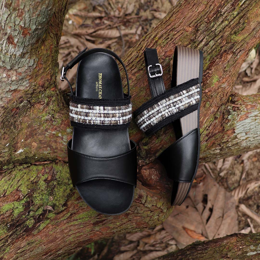 Full view of Thomas Chan’s Summer Love Duo-Strap Slingback Sandals in black, placed on a fallen wood surface. The image highlights the elegant duo straps, secure slingback design, and LiteStep flatform sole with light arch support, emphasizing their casual yet sophisticated style.