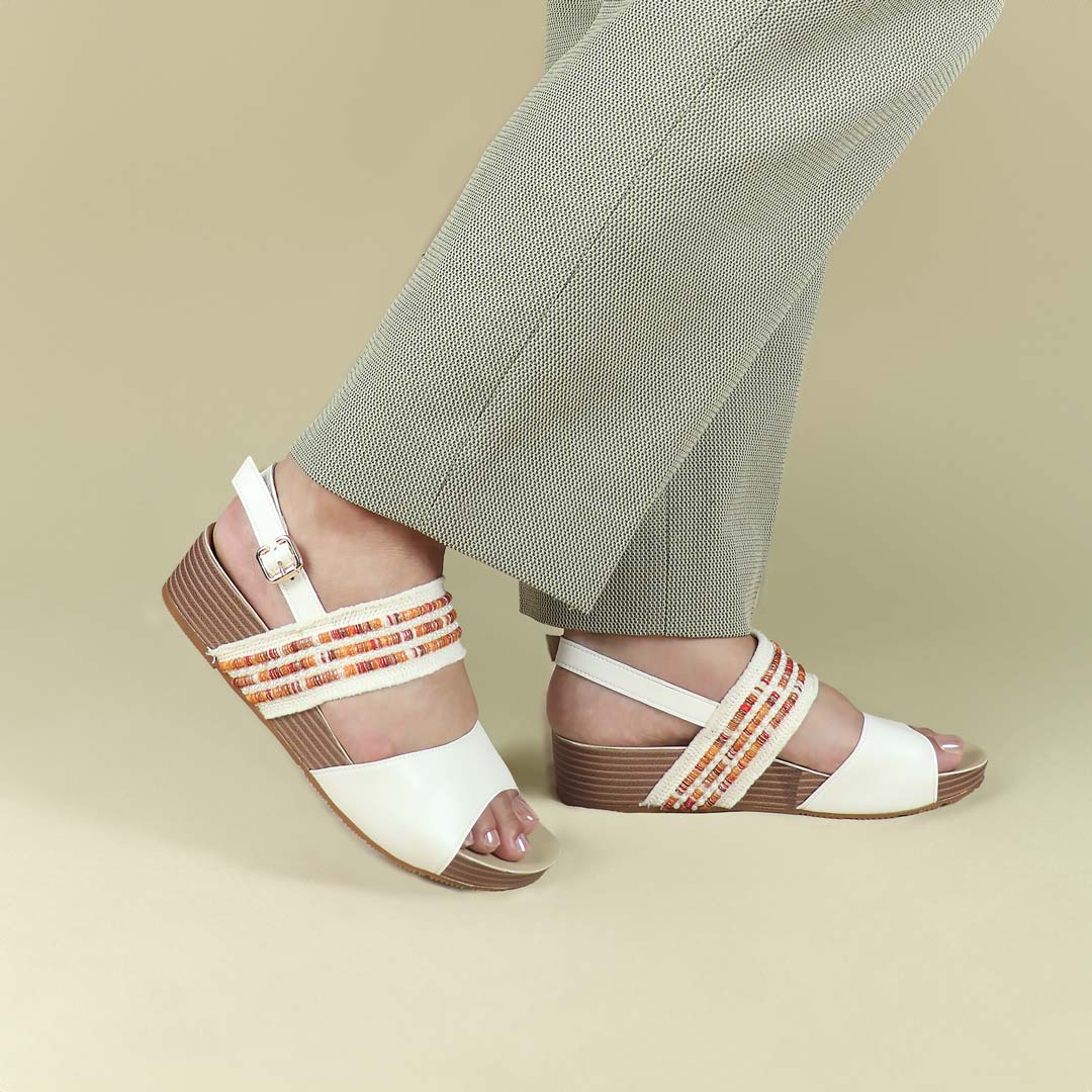 Side-angle view of Thomas Chan’s Summer Love Duo-Strap Slingback Sandals in ivory with a subtle touch of orange, showcased by a model against a cream studio backdrop, highlighting the elegant duo straps, a secure slingback design, and a LiteStep flatform sole with light arch support.