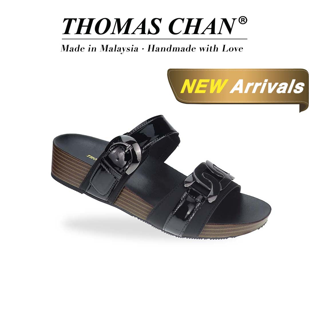 Diagonal view of Thomas Chan’s Metallic Duo-Strap Adjustable Sandals in black, showcasing sleek metallic straps, an adjustable buckle for a perfect fit, and a LiteStep flatform footbed for added comfort. The 'THOMAS CHAN®' brand logo is prominently displayed, with the inscription 'Made in Malaysia · Handmade with Love' beneath it. A gold and white banner highlights the special offer: 'New Arrival.'