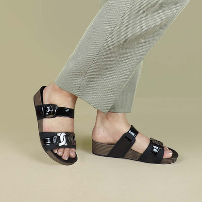 Side-angle view of Thomas Chan’s Metallic Duo-Strap Adjustable Sandals in black, modeled against a cream studio backdrop. The image highlights the sleek metallic straps, adjustable buckle design, and LiteStep flatform footbed, showcasing their modern elegance and all-day comfort.