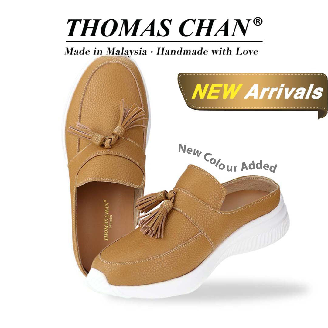  Thomas Chan Feather-Light Tassel Slide-On Loafers in camel, featuring a tassel bell design. "THOMAS CHAN®" brand displayed with "Made in Malaysia · Handmade with Love" below. Gold and white banner highlights special offer: "New Arrival" & "New Colour Added".