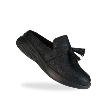 Diagonal view of Thomas Chan Feather-Light Tassel Slide-On Loafers in black, featuring a tassel bell design and a comfortable cushioned footbed.