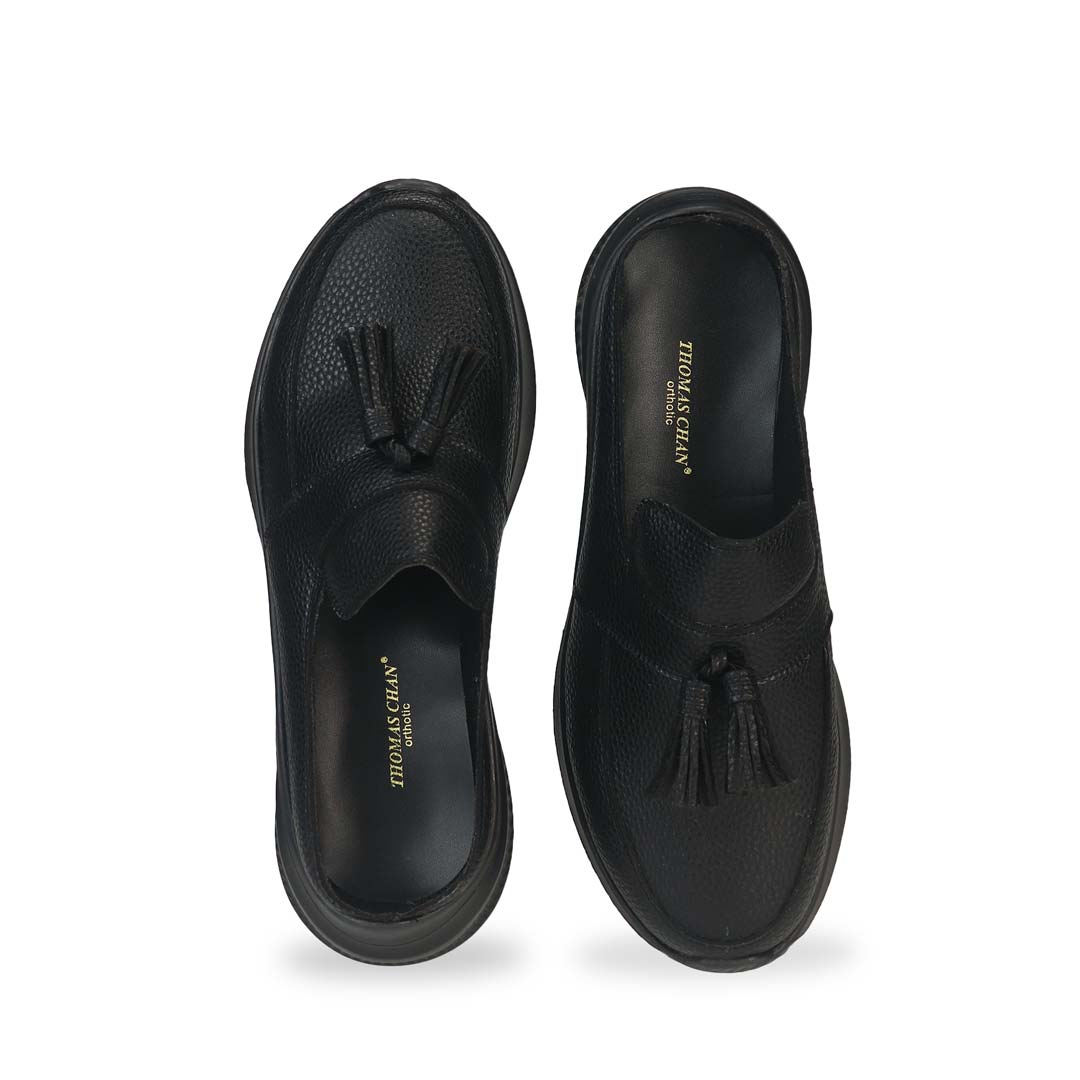 Front view of Thomas Chan Feather-Light Tassel Slide-On Loafers in black, featuring a tassel bell design and a comfortable cushioned footbed.