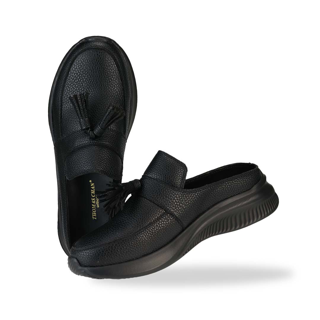 Full view of Thomas Chan Feather-Light Tassel Slide-On Loafers in black, featuring a tassel bell design and a comfortable cushioned footbed.