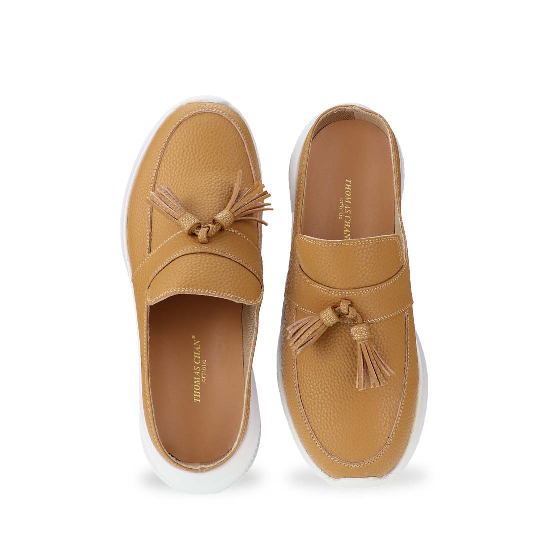 Front view of Thomas Chan Feather-Light Tassel Slide-On Loafers in camel, featuring a tassel bell design and a comfortable cushioned footbed.