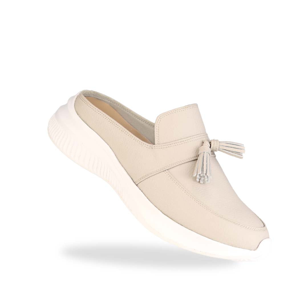 Diagonal view of Thomas Chan Feather-Light Tassel Slide-On Loafers in ivory, featuring a tassel bell design and a comfortable cushioned footbed.