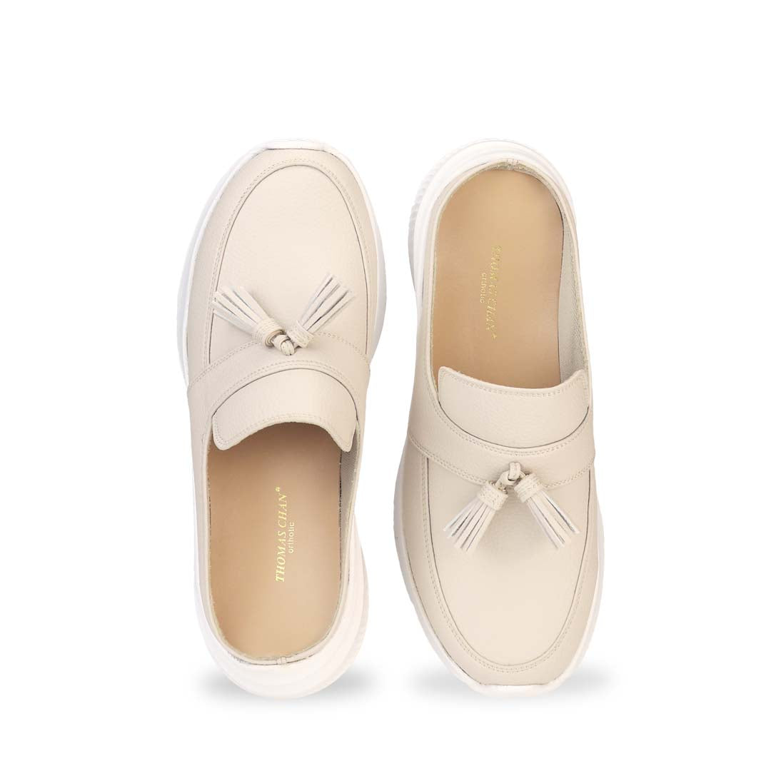 Front view of Thomas Chan Feather-Light Tassel Slide-On Loafers in ivory, featuring a tassel bell design and a comfortable cushioned footbed.