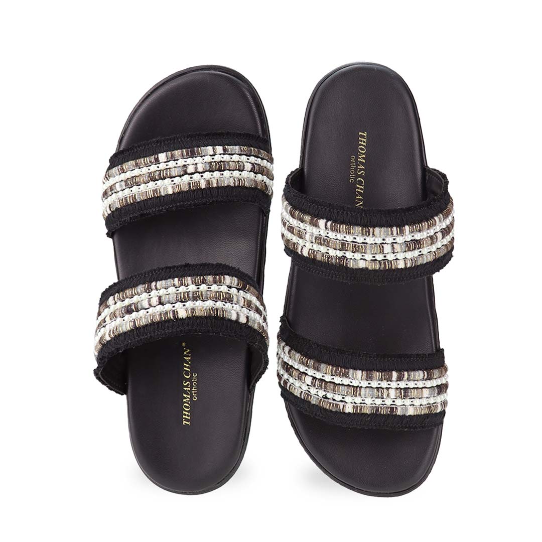 Front view of Thomas Chan Summer Love Boho low platform sandals in black and little white embroidery, featuring a comfort footbed. The platform, with a black braided element, measures 3cm at the front and 5cm at the back.