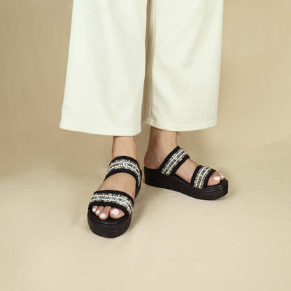 Model wearing size 37 Thomas Chan Summer Love Boho low platform sandals in black with little white embroidery from the front view, featuring a comfort footbed. The platform, with a black braided element, measures 3cm at the front and 5cm at the back