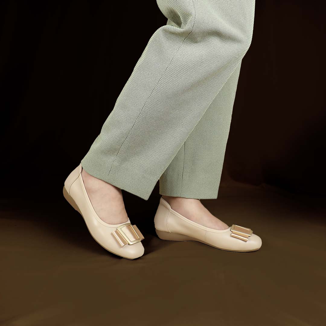 A model wearing the cream colour Thomas Chan's Soft Calf Leather Ribbon Ballet Pumps in a studio setting, paired with office attire, demonstrating their elegant and professional appearance.