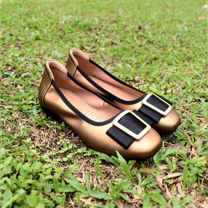 The bronze colour Thomas Chan's Soft Calf Leather Ribbon Ballet Pumps arranged on lush green grass, with natural lighting enhancing their texture and details.