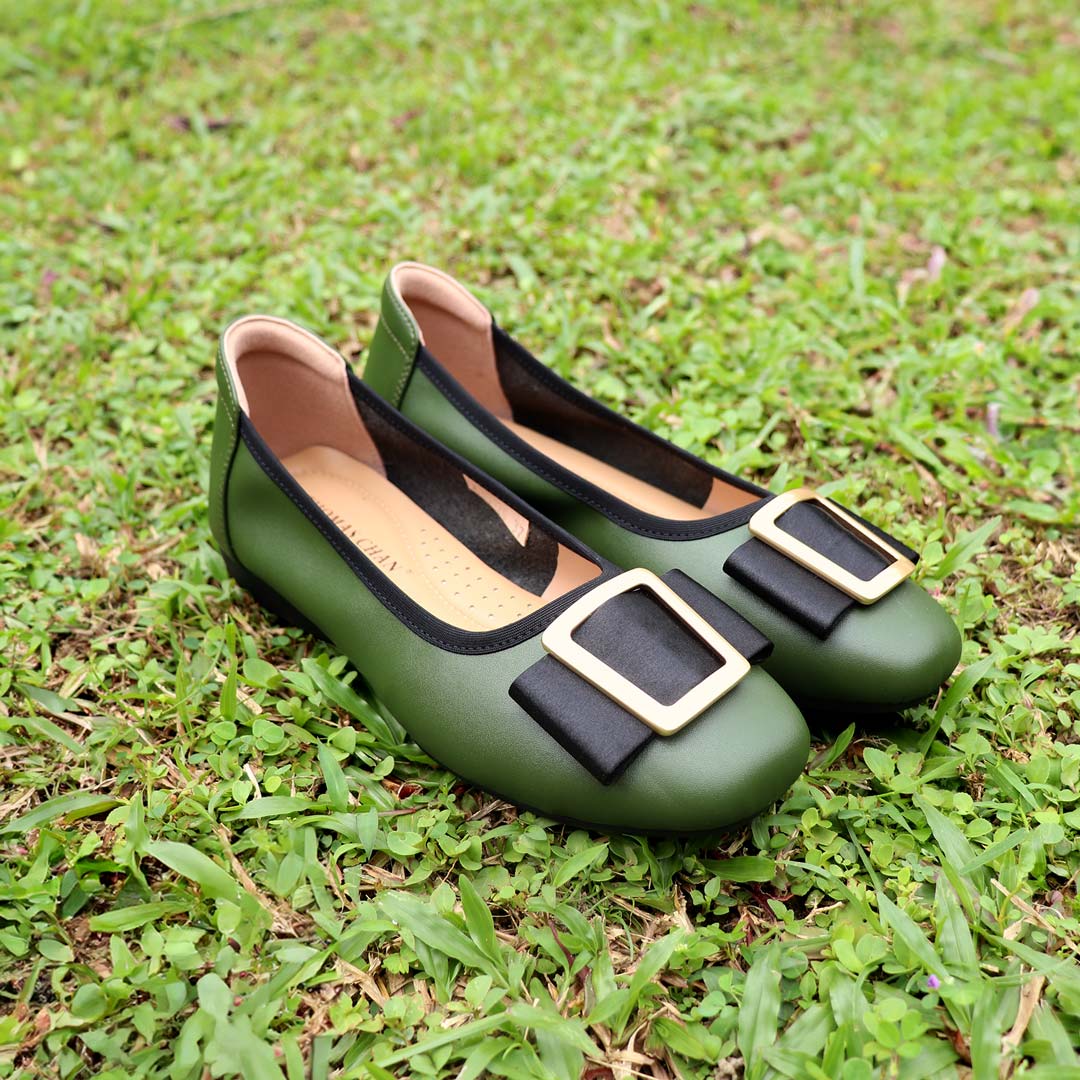 The deep green colour Thomas Chan's Soft Calf Leather Ribbon Ballet Pumps arranged on lush green grass, with natural lighting enhancing their texture and details.