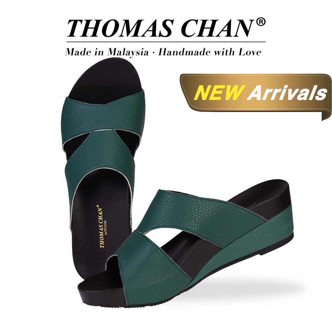 Thomas Chan's Pebble Lychee Everyday Low Wedge Slides in dark green, featuring an arch-support footbed. The "THOMAS CHAN®" brand is displayed with "Made in Malaysia · Handmade with Love" below. A gold and white banner highlights a special offer: "New Arrival."