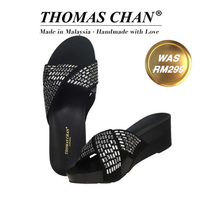 Thomas Chan Diamond Crisscross Suede Low Wedges in black, featuring an elegant design and arch-support footbed. "THOMAS CHAN®" brand displayed with "Made in Malaysia · Handmade with Love" below. Gold and white banner highlights special offer: "Was RM299"