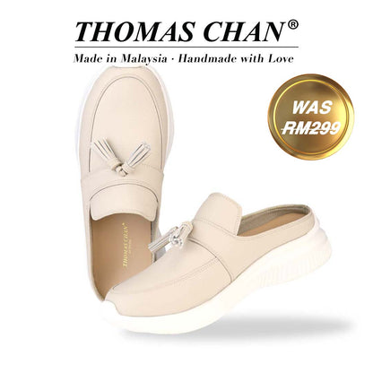 Thomas Chan Feather-Light Tassel Slide-On Loafers in camel, featuring a tassel bell design. "THOMAS CHAN®" brand displayed with "Made in Malaysia · Handmade with Love" below. Gold and white banner highlights special offer: "WAS RM299" 