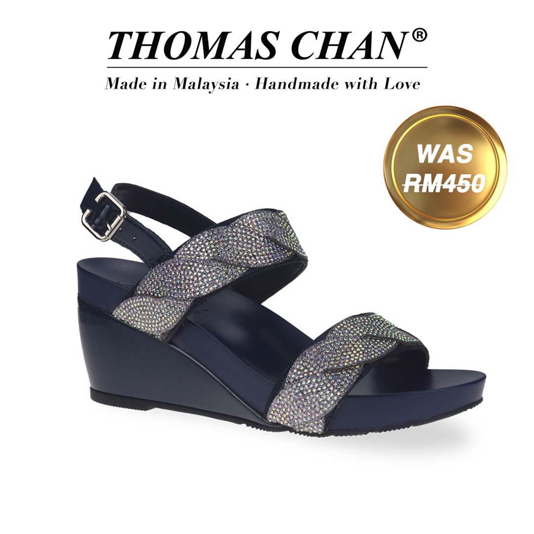 Thomas Chan's Diamond Braided Slingback Wedges in blue patent feature rhinestone strappy decoration and a 3-inch wedge heel. They are designed with built-in arch-support footbed technology for enduring comfort. A gold badge displays the original price of RM450, accompanied by text celebrating "THOMAS CHAN® Made in Malaysia · Handmade with Love."