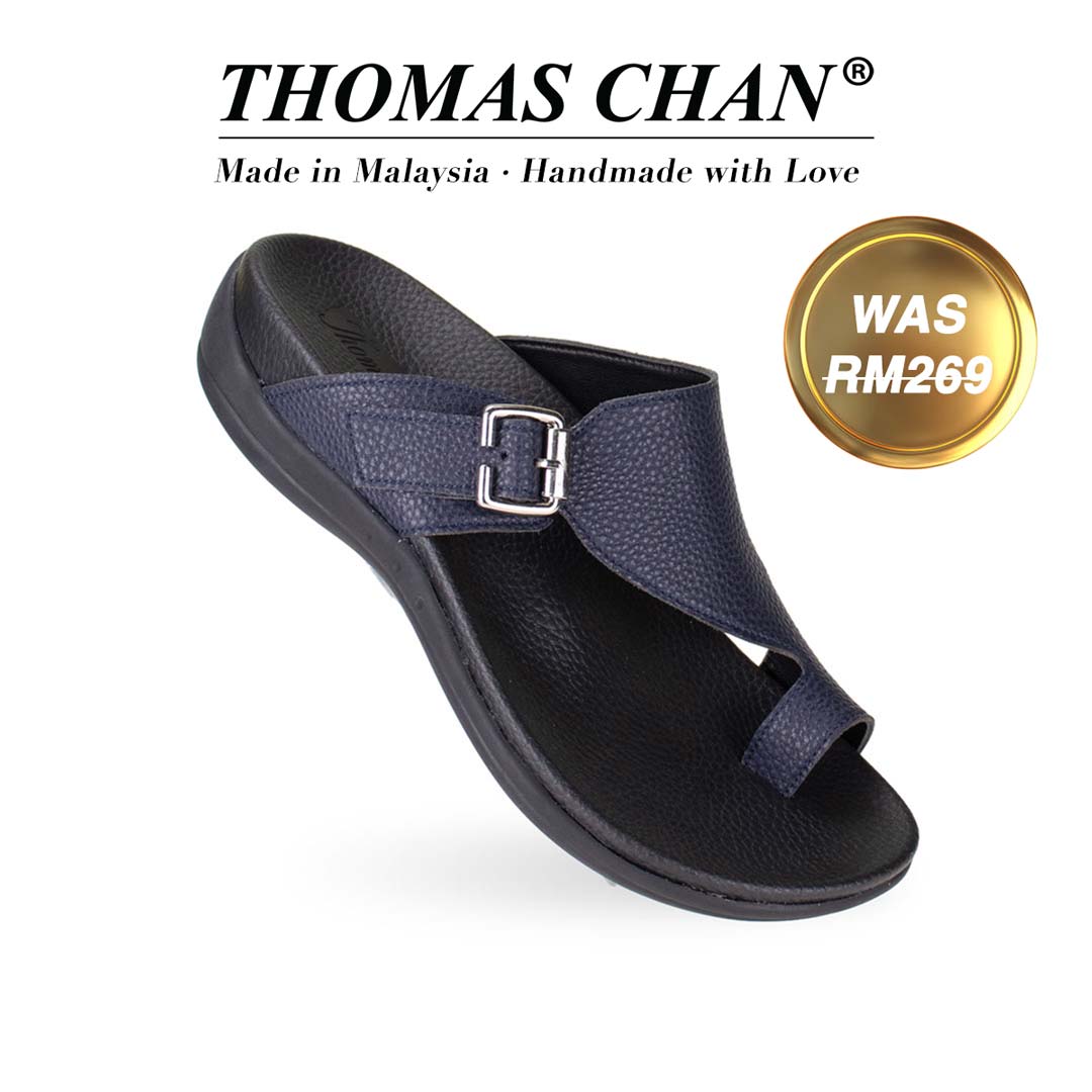 Thomas Chan's Toe-Strap Flat Sandals in blue, displaying an elegant design with an arch-support footbed. "THOMAS CHAN®" brand prominently shown with "Made in Malaysia · Handmade with Love" below. Gold and white banner highlights special offer: "WAS 269."