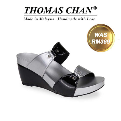 Image of a stylish black and silver wedge sandal from Thomas Chan. The sandal features a glossy strappy design with metallic studs and a 3-inch wedge heel with arch-support footbed technology. A gold badge shows the original price was RM369, with text above reading "THOMAS CHAN® Made in Malaysia · Handmade with Love."