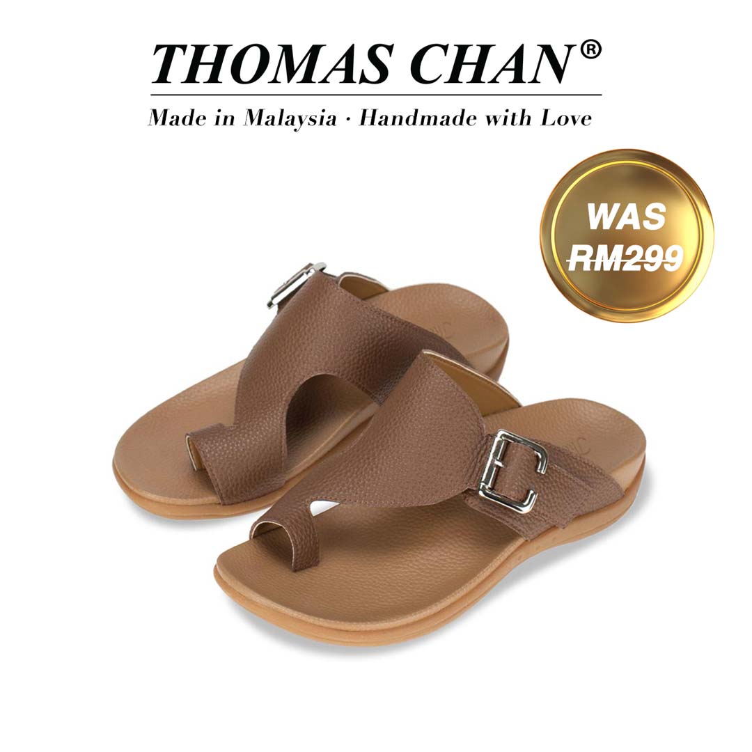 An image of Thomas Chan's Men Toe Loop Buckle Sandals in light brown colour, featuring an arch-support footbed. The top of the image displays the brand name "THOMAS CHAN®" with the text "Made in Malaysia · Handmade with Love" below it. A gold and white banner on the right side states "WAS 299."